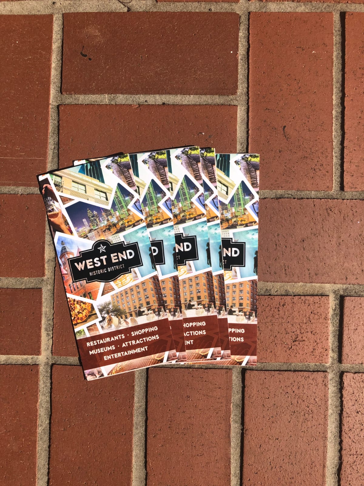 Printed West End visitor brochures fanned on a brick sidewalk